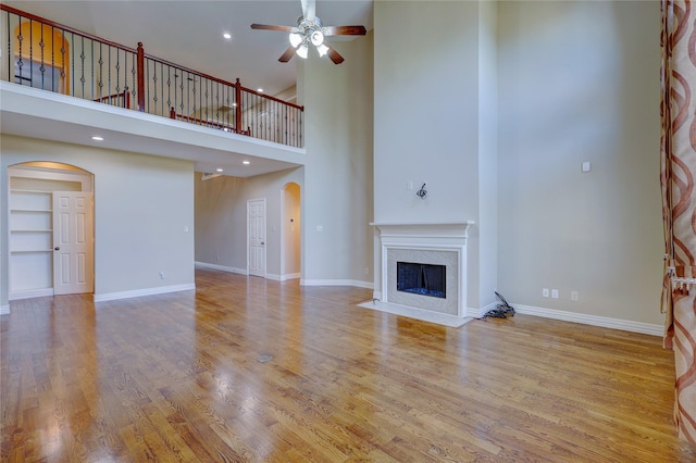 5507 Opal Cove Ct, Katy, TX 77494 - unfurnished living room featuring arched walkways, ceiling fan, a high end fireplace, and a towering ceiling
