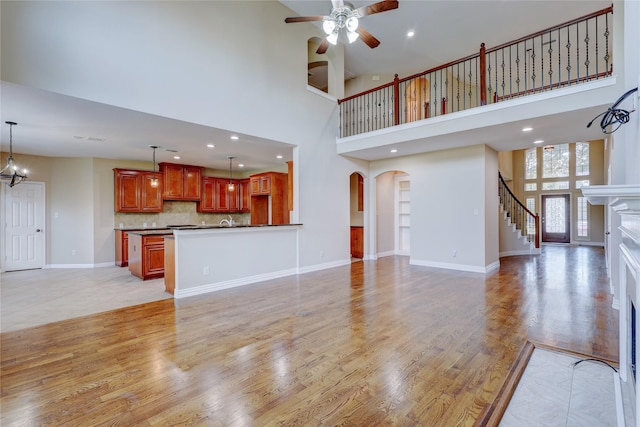 5507 Opal Cove Ct, Katy, TX 77494 - unfurnished living room featuring light wood-style floors, arched walkways, a towering ceiling, and ceiling fan