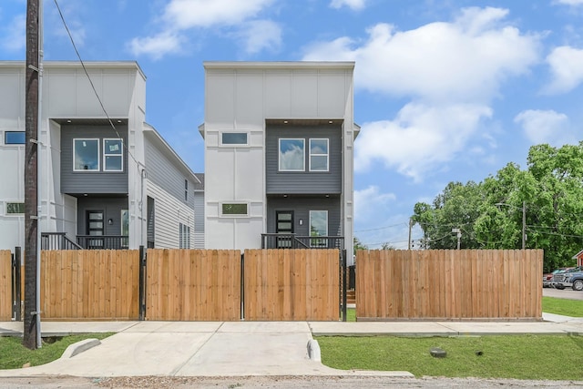 contemporary home featuring a fenced front yard, board and batten siding, and a gate