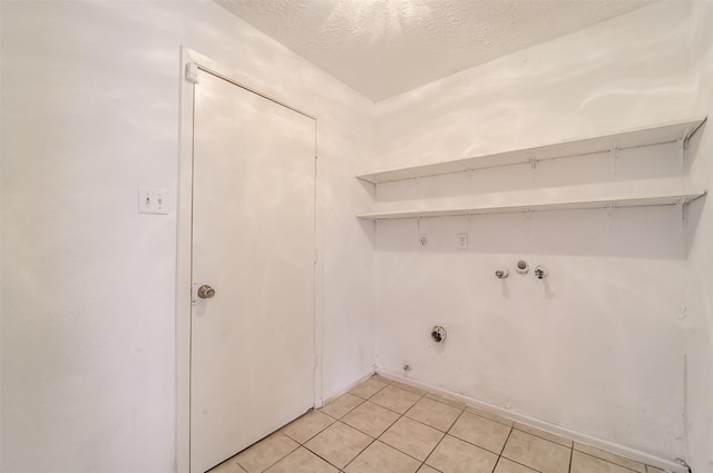 laundry area with laundry area, a textured ceiling, washer hookup, light tile patterned floors, and hookup for a gas dryer