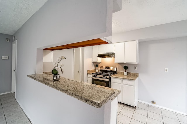 kitchen with baseboards, stainless steel range with gas cooktop, a textured ceiling, under cabinet range hood, and light tile patterned floors