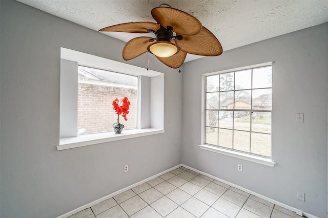 spare room featuring a ceiling fan, baseboards, plenty of natural light, and light tile patterned floors