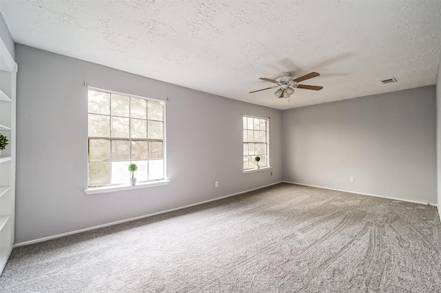 empty room with visible vents, a textured ceiling, and ceiling fan