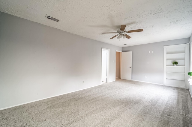 unfurnished room featuring ceiling fan, carpet flooring, a textured ceiling, and visible vents