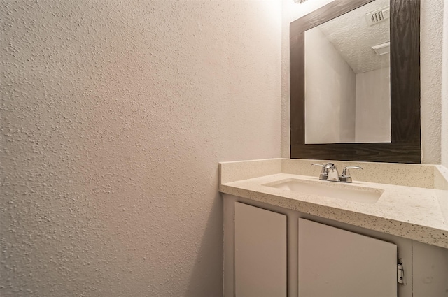 bathroom featuring vanity, a textured ceiling, and a textured wall