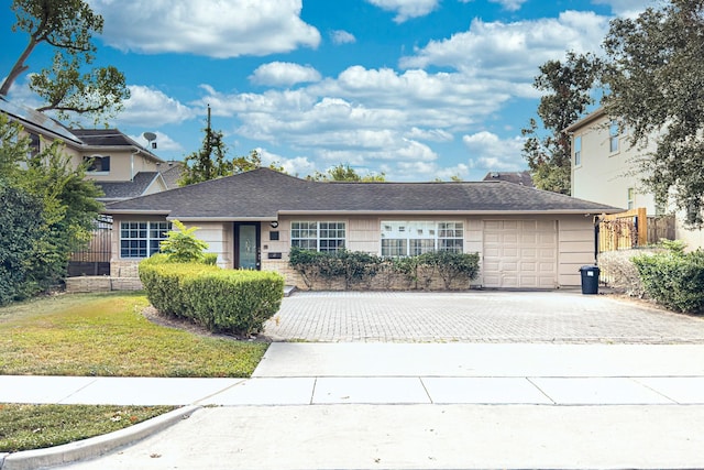 ranch-style house with an attached garage, fence, driveway, and a front yard