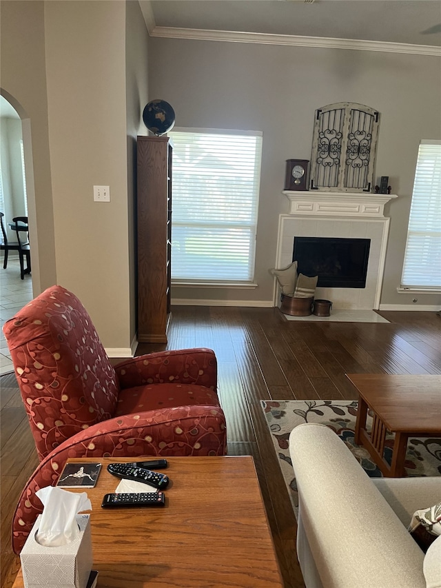 living area featuring crown molding, a fireplace, arched walkways, and hardwood / wood-style flooring