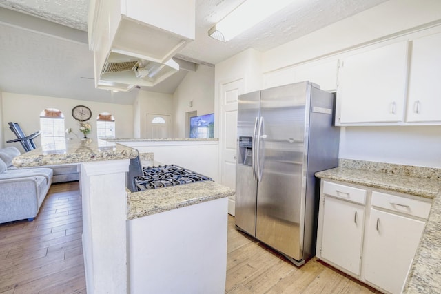 kitchen featuring light wood-style floors, stainless steel fridge, a center island, white cabinets, and light stone counters