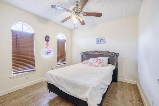 bedroom featuring a textured ceiling, baseboards, and wood finished floors