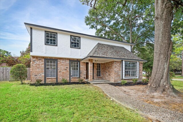 traditional-style house featuring stucco siding, brick siding, and a front yard