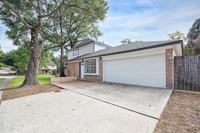 traditional home featuring fence, brick siding, a shingled roof, an attached garage, and driveway