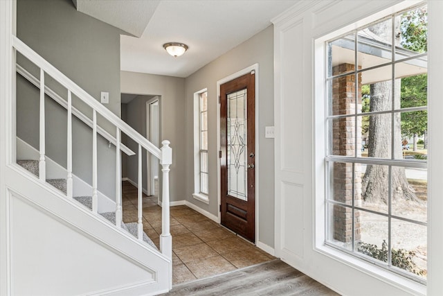 tiled foyer entrance with plenty of natural light and stairs
