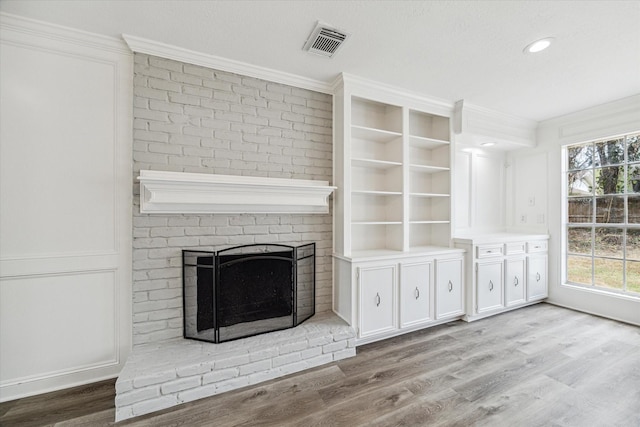 unfurnished living room with visible vents, ornamental molding, wood finished floors, a fireplace, and recessed lighting