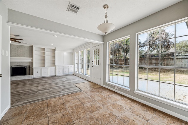 unfurnished sunroom featuring visible vents and plenty of natural light