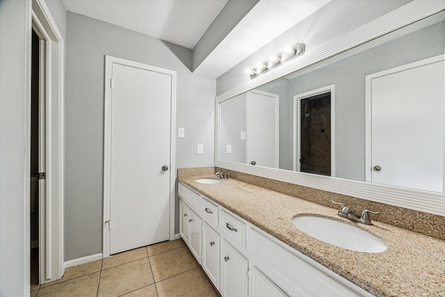 full bath featuring a sink, baseboards, tile patterned flooring, and double vanity