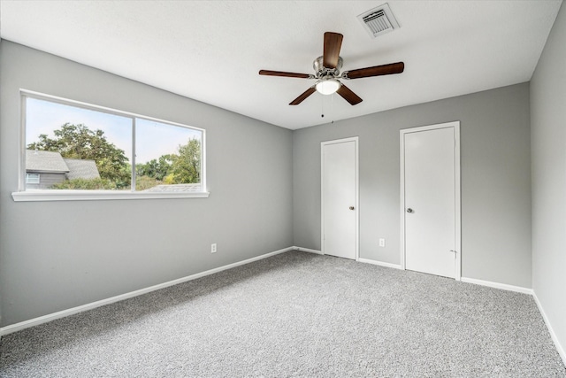 unfurnished bedroom with visible vents, carpet flooring, baseboards, and ceiling fan