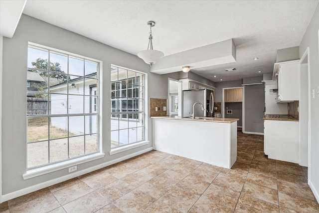 kitchen featuring a peninsula, stainless steel fridge, and a wealth of natural light