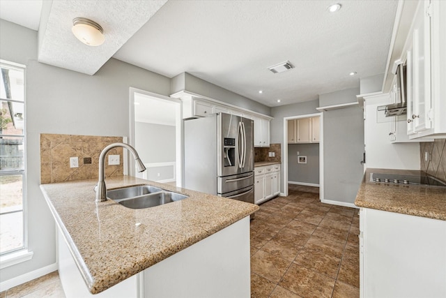 kitchen featuring black electric stovetop, a sink, stainless steel fridge with ice dispenser, a peninsula, and decorative backsplash