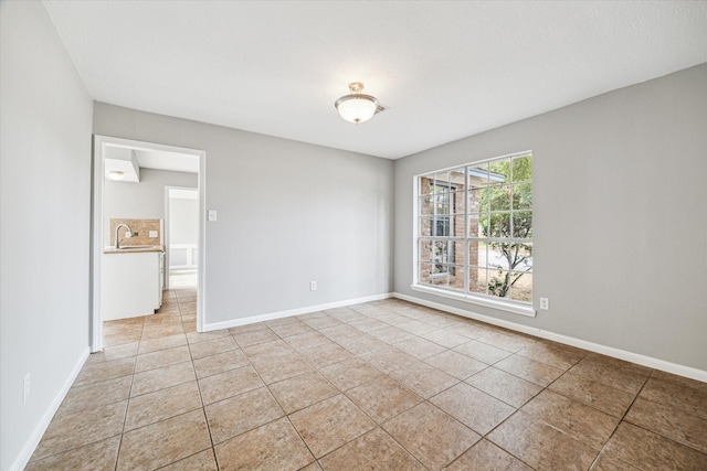 unfurnished room with light tile patterned flooring and baseboards