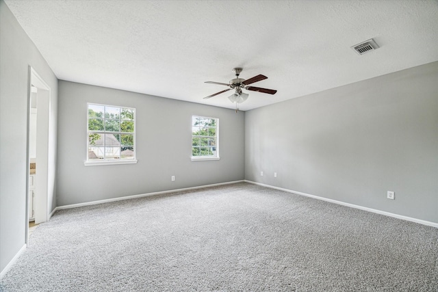 spare room with a ceiling fan, a textured ceiling, visible vents, carpet floors, and baseboards
