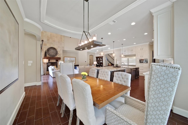 dining space with arched walkways, baseboards, recessed lighting, dark wood-style floors, and crown molding