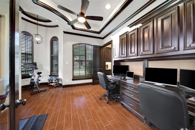 office featuring crown molding, a ceiling fan, baseboards, built in study area, and dark wood finished floors