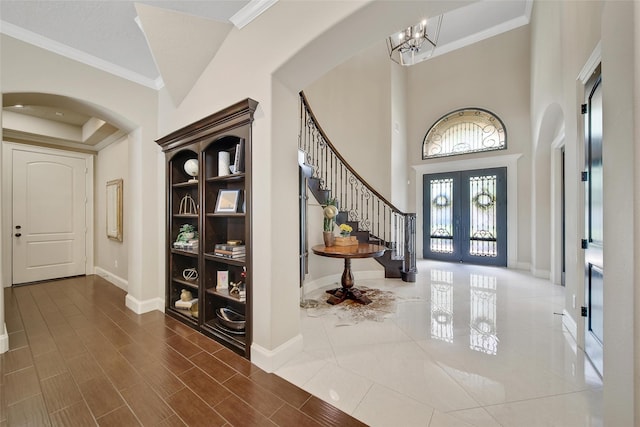 entryway featuring arched walkways, french doors, stairs, a chandelier, and baseboards