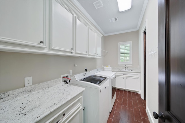 washroom with cabinet space, crown molding, washing machine and clothes dryer, and wood finish floors