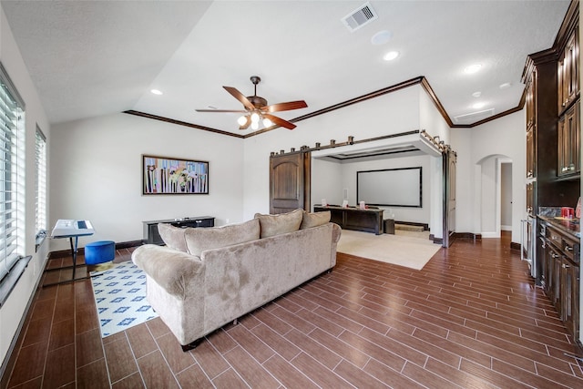 living area with arched walkways, a ceiling fan, baseboards, a barn door, and vaulted ceiling