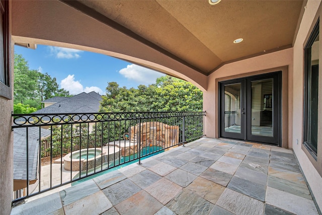 view of patio featuring french doors, a balcony, and a pool with connected hot tub