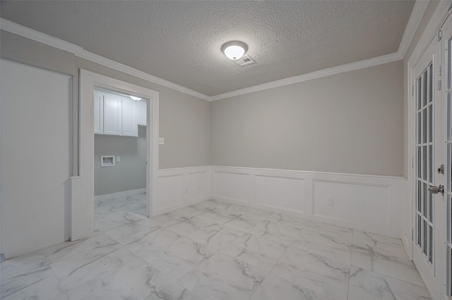 spare room featuring visible vents, a textured ceiling, a decorative wall, and a wainscoted wall