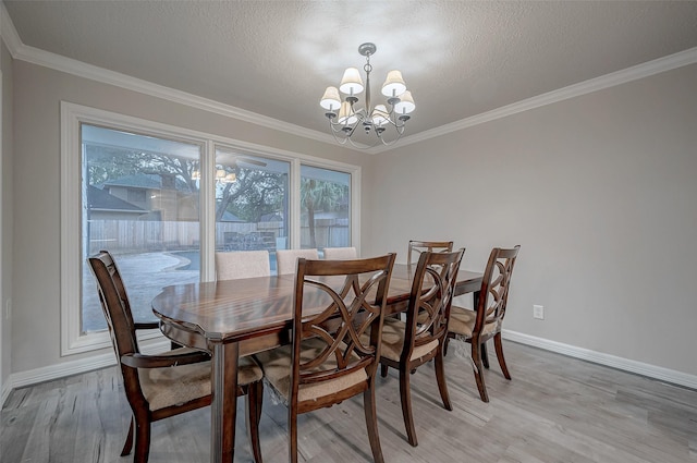 dining space with a healthy amount of sunlight, crown molding, light wood-type flooring, and a chandelier