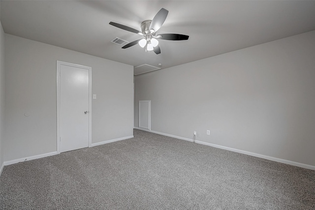 carpeted spare room with visible vents, attic access, baseboards, and ceiling fan