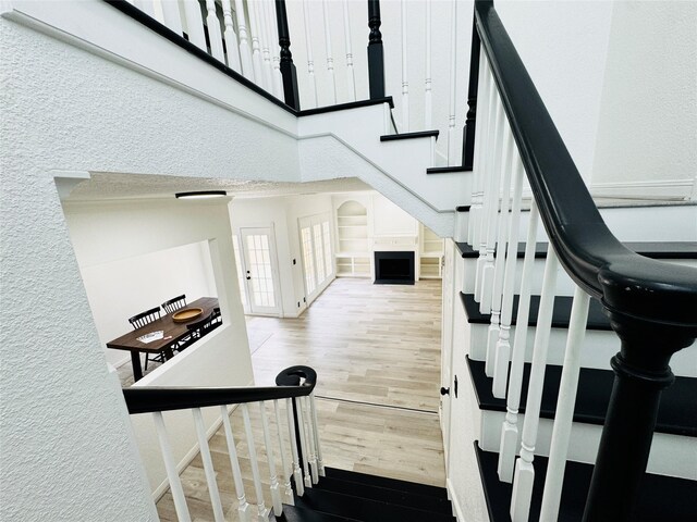 2323 Augusta Dr Unit 43, Houston, TX 77057 - staircase with wood finished floors, a towering ceiling, a textured wall, and baseboards