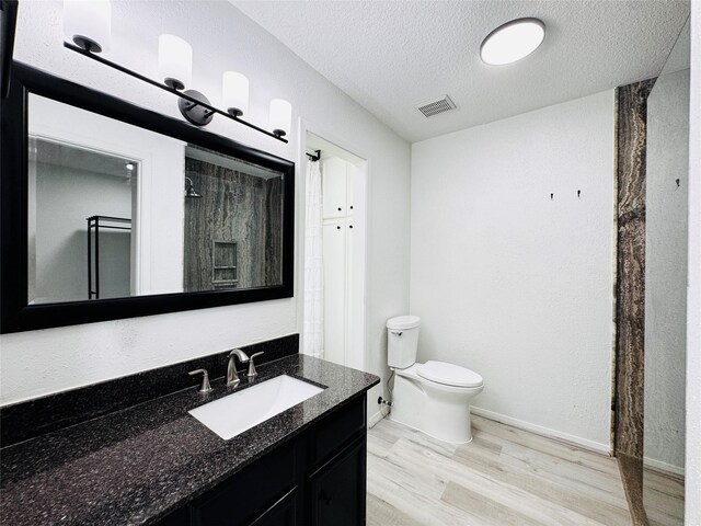 2323 Augusta Dr Unit 43, Houston, TX 77057 - bathroom featuring vanity, wood finished floors, toilet, a textured ceiling, and baseboards
