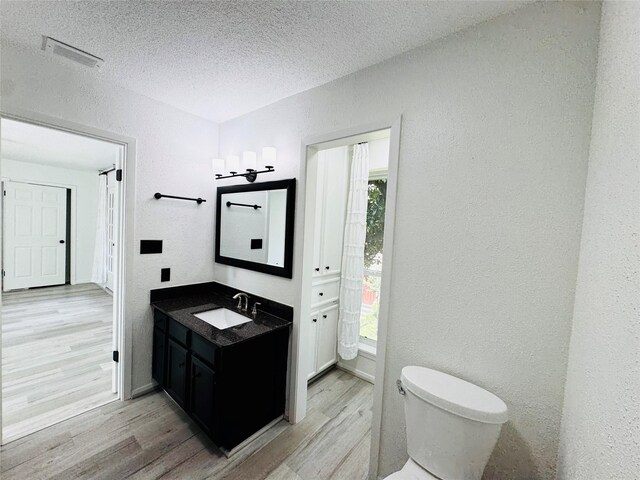 2323 Augusta Dr Unit 43, Houston, TX 77057 - bathroom with toilet, wood finished floors, vanity, a textured ceiling, and healthy amount of natural light
