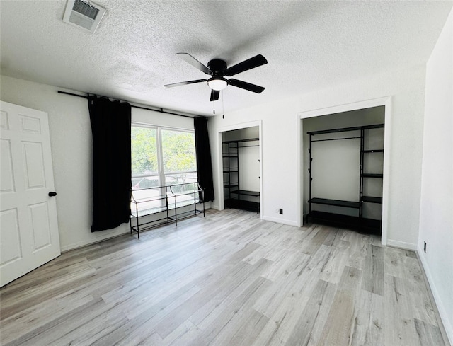 2323 Augusta Dr Unit 43, Houston, TX 77057 - unfurnished bedroom featuring wood finished floors, a textured ceiling, baseboards, a ceiling fan, and a barn door