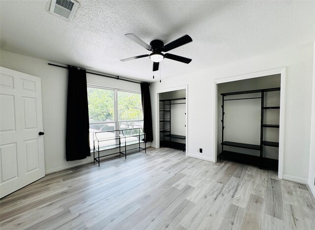 2323 Augusta Dr Unit 43, Houston, TX 77057 - unfurnished bedroom featuring light wood-style floors, a textured ceiling, baseboards, a ceiling fan, and multiple closets