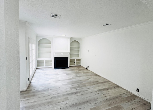 2323 Augusta Dr Unit 43, Houston, TX 77057 - unfurnished living room with crown molding, light wood-style flooring, a textured ceiling, built in shelves, and a fireplace