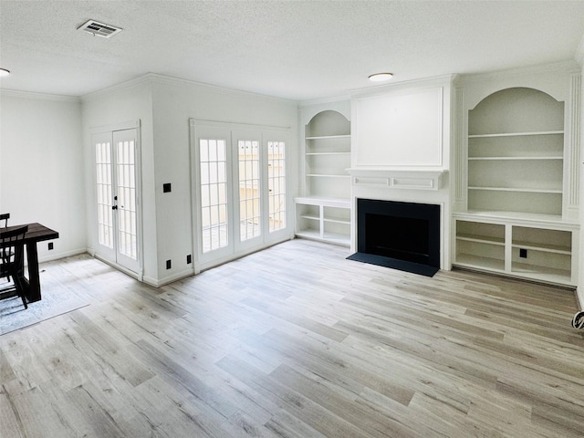 2323 Augusta Dr Unit 43, Houston, TX 77057 - unfurnished living room with a textured ceiling, wood finished floors, ornamental molding, built in shelves, and a fireplace with flush hearth