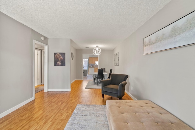 1016 E Tri Oaks Ln Unit 79, Houston, TX 77043 - sitting room with a textured ceiling, baseboards, and light wood-style flooring