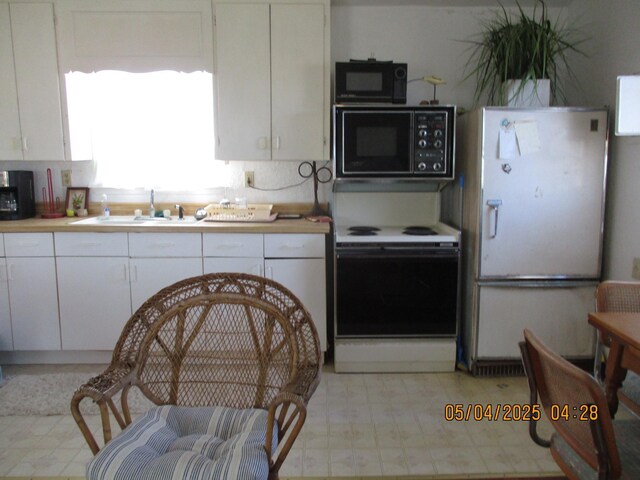 kitchen featuring a sink, light floors, white cabinets, and white appliances