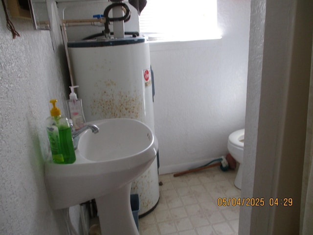 half bathroom featuring toilet, tile patterned floors, and a textured wall