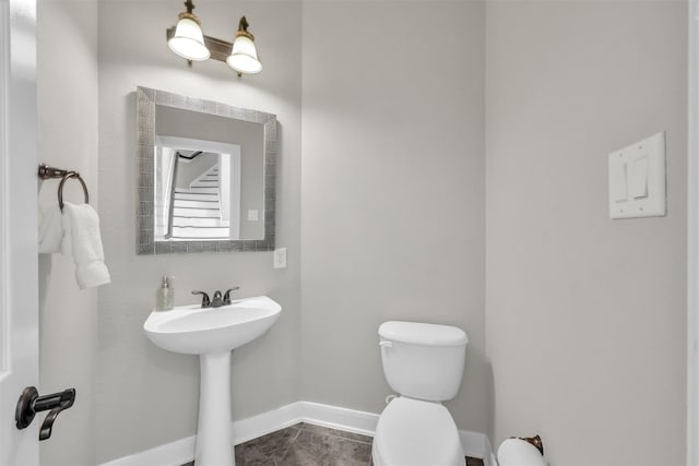 half bathroom featuring baseboards and toilet