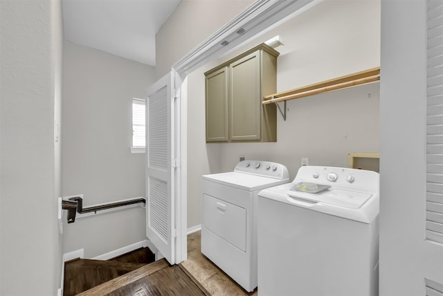 clothes washing area featuring separate washer and dryer and cabinet space