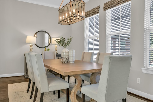 dining area featuring baseboards, wood finished floors, and a notable chandelier