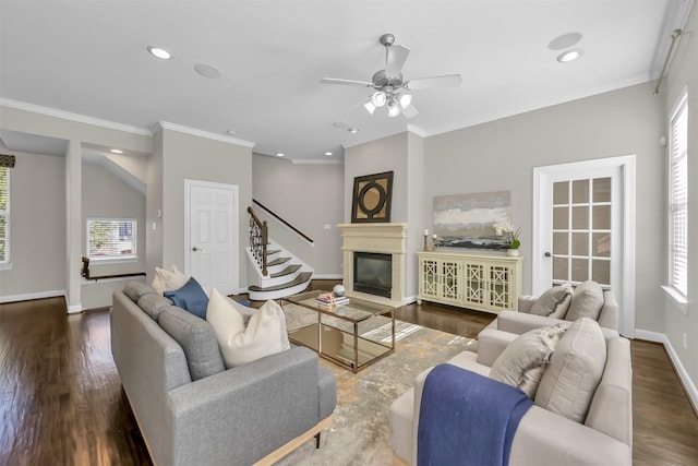 living area with a ceiling fan, baseboards, ornamental molding, and wood finished floors