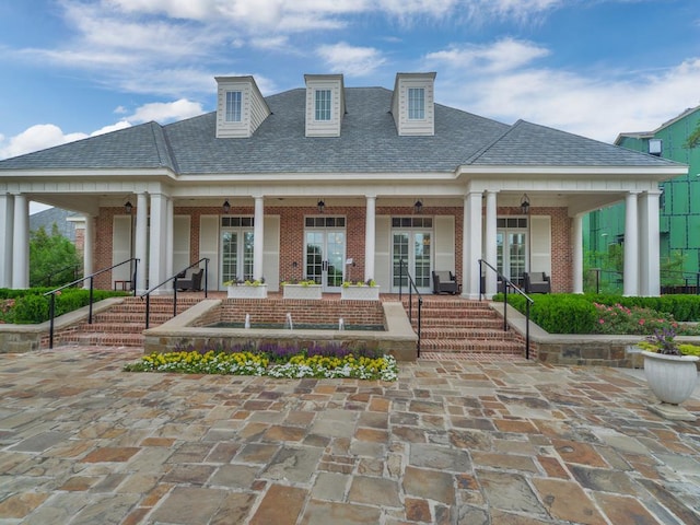 back of property with brick siding, a shingled roof, french doors, and a patio