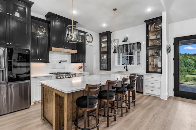 224 Kellog, Fischer, TX 78623 - kitchen with dark cabinets, stainless steel appliances, glass insert cabinets, backsplash, and light wood-style floors
