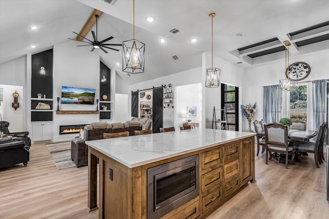 224 Kellog, Fischer, TX 78623 - kitchen with stainless steel microwave, open floor plan, light wood-type flooring, a center island, and beamed ceiling